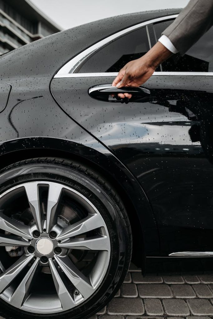 pexels photo 8425057 Close-up of a hand opening a black luxury car door on a rainy day. Elegant and modern design.